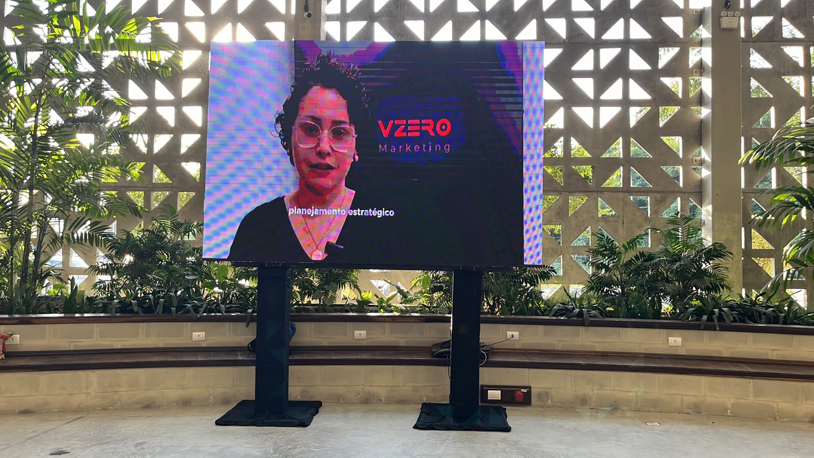 Painel de LED 3x2 em hall de evento corporativo com palestra ao vivo